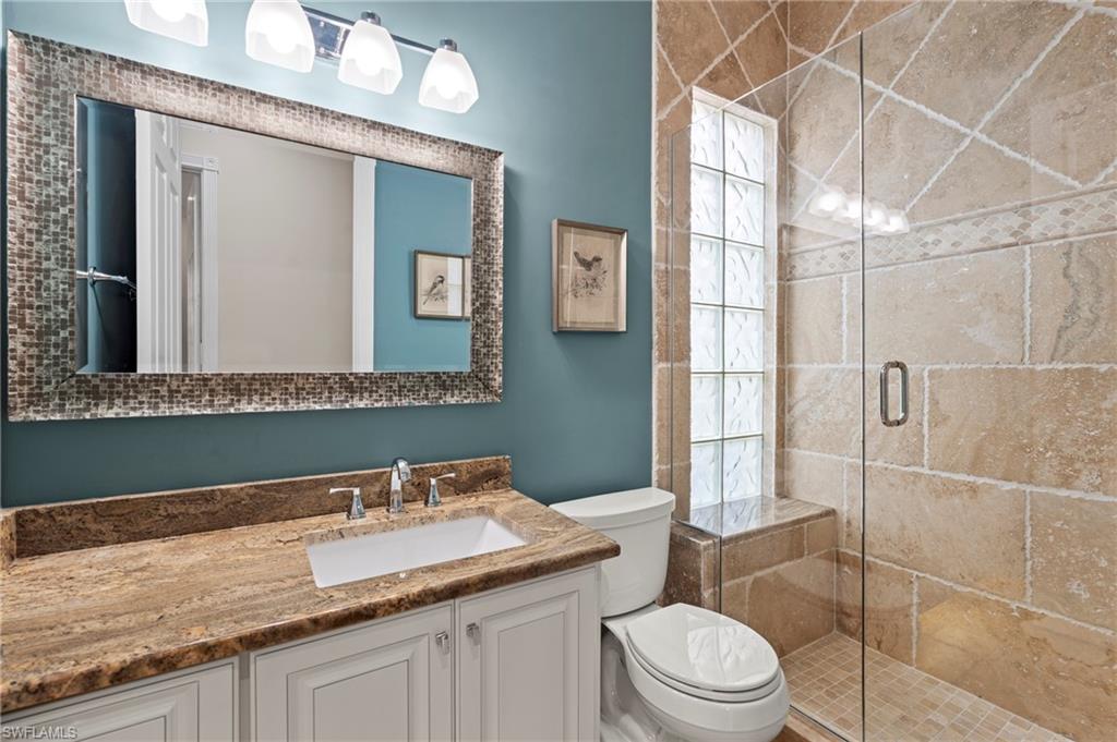 4401 Novato Court Naples, FL 34109 - Photo 36 of 50 a bathroom with a granite countertop toilet a sink and a mirror