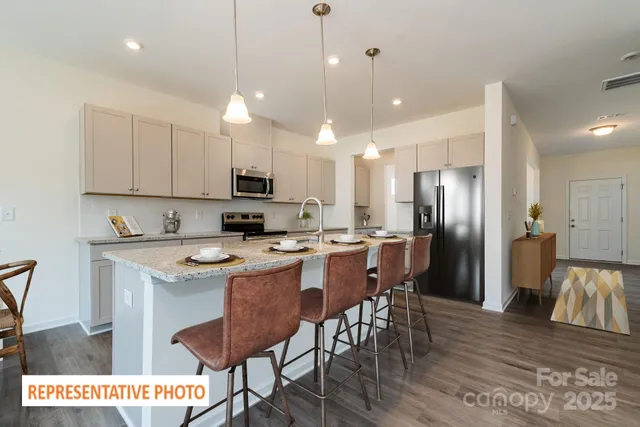 a kitchen with stainless steel appliances granite countertop a sink a stove a refrigerator and a dining table with wooden floor