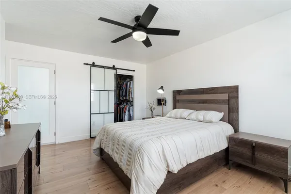 a bedroom with a bed a dresser and a chandelier
