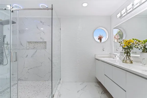 a bathroom with a granite countertop sink a mirror and shower