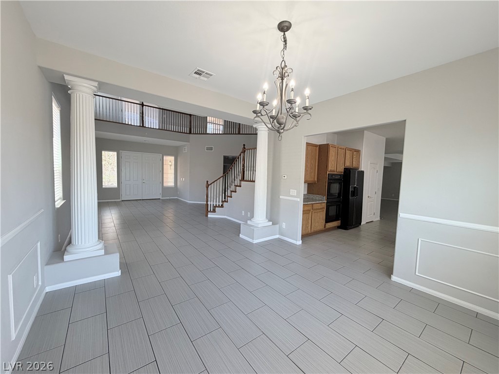 6116 Rabbit Track Street Las Vegas, NV 89130 - Photo 3 of 28 A spacious entry foyer features architectural columns and a grand staircase, showcasing elegant tile flooring throughout.
