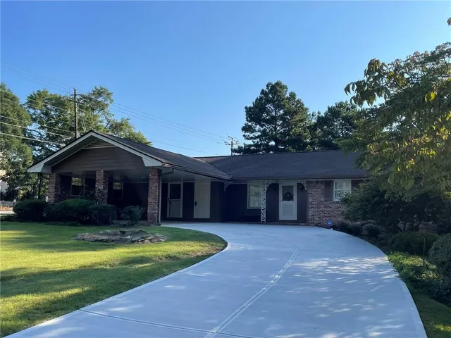 a view of a house with a yard plants and large tree