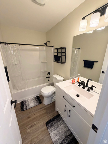 450 13800 South, Unit 2 Draper, UT 84020 - Photo 10 of 21 Bathroom featuring a white vanity with integrated sink, matte black fixtures, wood-finish flooring, a white bathtub with shower, and a frameless mirror