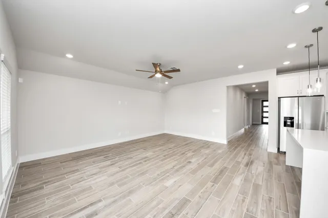 a view of an empty room with wooden floor and a window