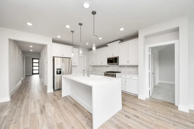 a view of a kitchen with kitchen island a sink stainless steel appliances and cabinets