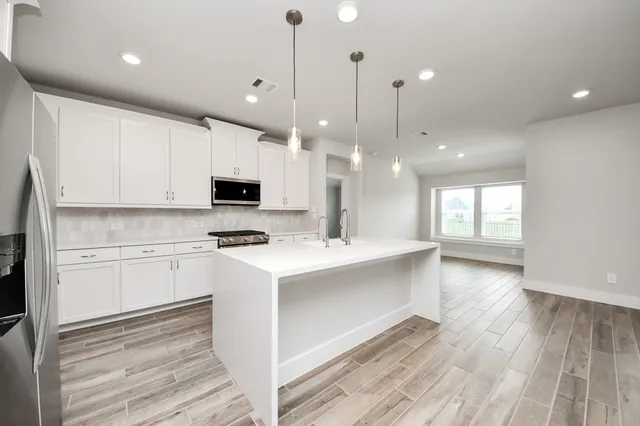 a large kitchen with stainless steel appliances granite countertop a sink a stove and a refrigerator