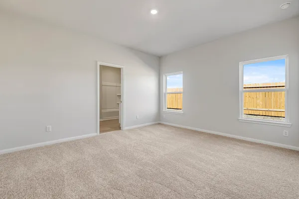 a view of an empty room with wooden floor and a ceiling fan