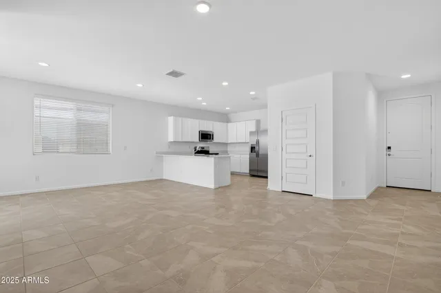 a view of kitchen with refrigerator and white cabinets
