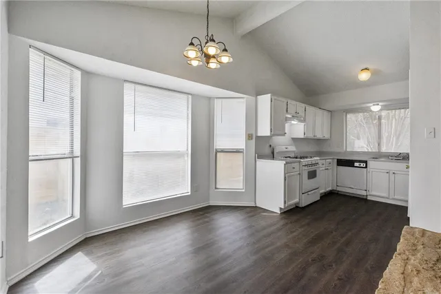 a kitchen with stainless steel appliances kitchen island granite countertop a refrigerator a sink dishwasher a stove and white cabinets with wooden floor