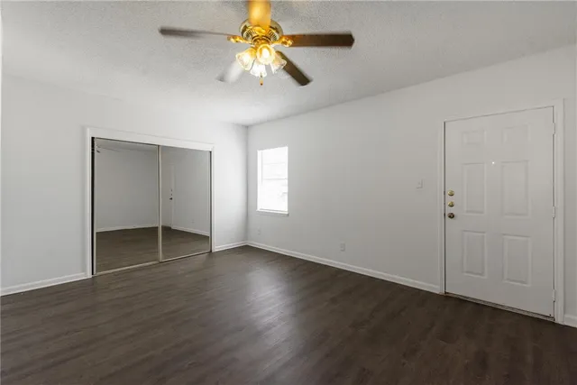 an empty room with wooden floor closet and windows