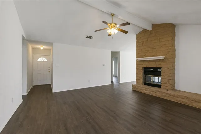 a view of an empty room with wooden floor and a fireplace