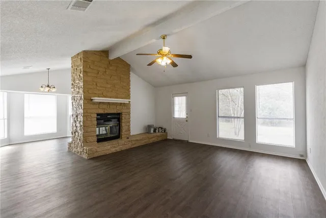 an empty room with windows fireplace and wooden floor