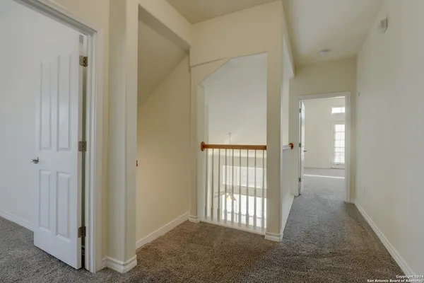 an empty room with a chandelier fan and windows