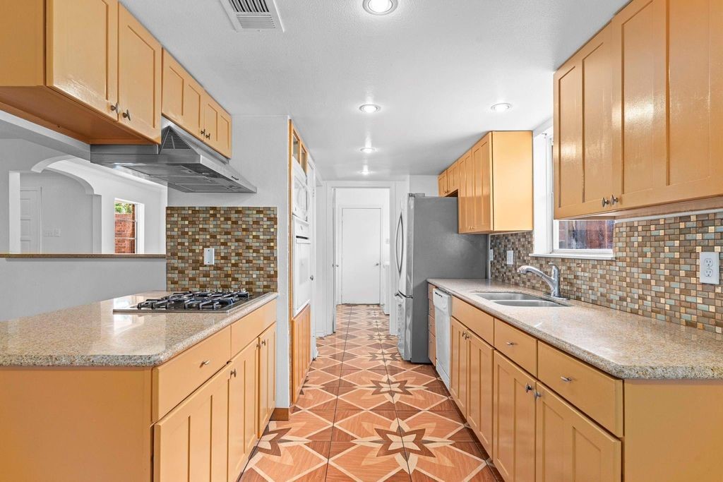8918 Grape Street Houston, TX 77036 - Photo 11 of 40 a kitchen with granite countertop a sink stove and cabinets
