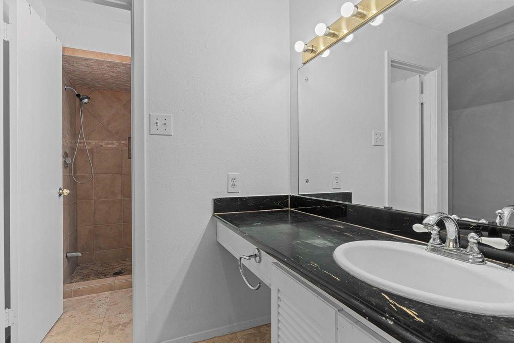 8918 Grape Street Houston, TX 77036 - Photo 32 of 40 a bathroom with a granite countertop sink and a mirror