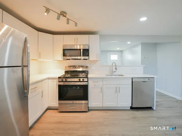 a kitchen with white cabinets and stainless steel appliances