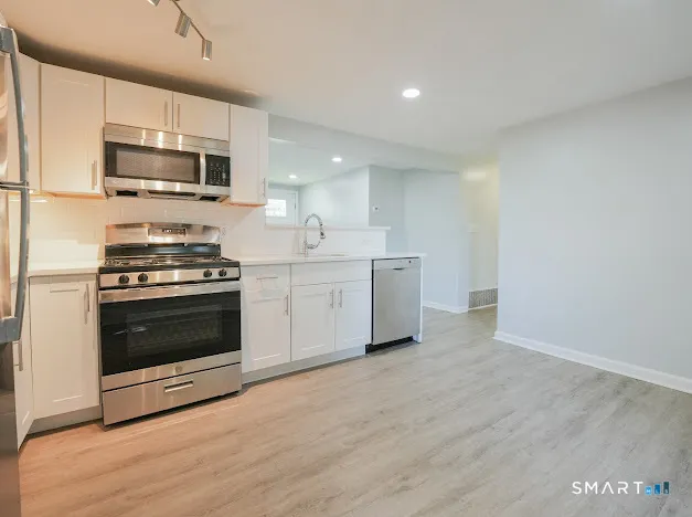 a kitchen with stainless steel appliances a stove a microwave and white cabinets