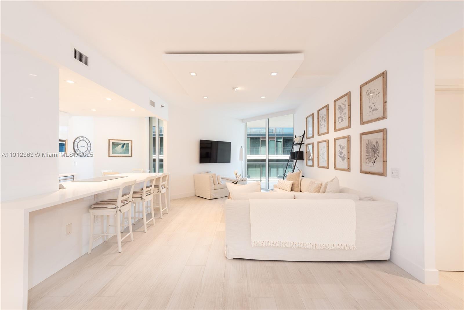 8925 Collins Avenue, Unit 11C Surfside, FL 33154 - Photo 9 of 36 a large white room with a large window and flat screen tv