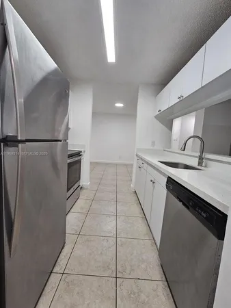 a kitchen with granite countertop a refrigerator and a sink