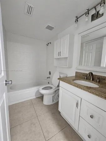 a spacious bathroom with a granite countertop sink a toilet mirror and bathtub