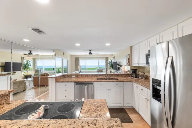 a open kitchen with stainless steel appliances granite countertop a refrigerator and a stove top oven