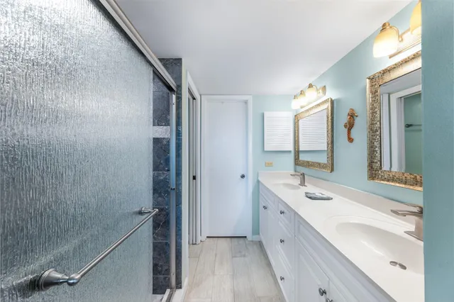 a spacious bathroom with a double vanity sink a mirror and a shower