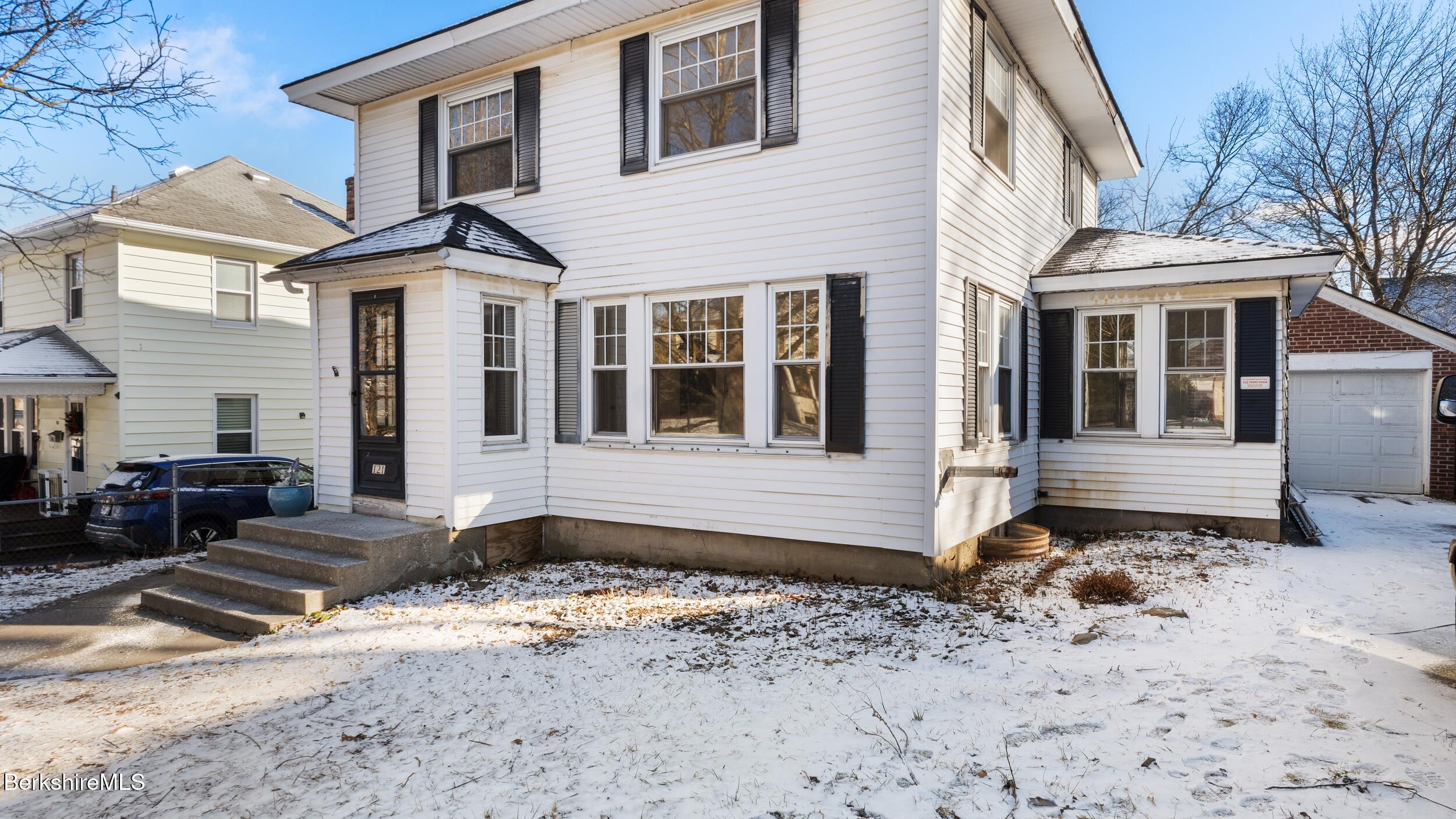 a front view of a house with a yard covered in snow