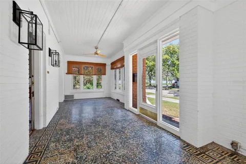 a view of a hallway to an empty room with wooden floor and a window