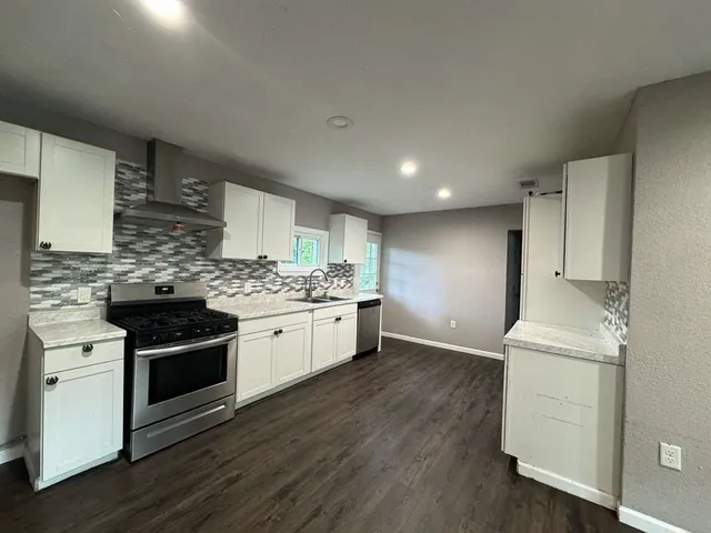 a kitchen with stainless steel appliances kitchen island granite countertop a stove a sink and a refrigerator