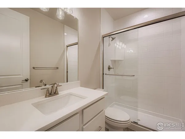 a bathroom with a sink a toilet a mirror and shower