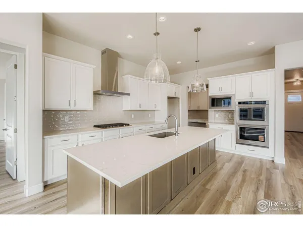 a kitchen with kitchen island a stove a sink a refrigerator and chairs