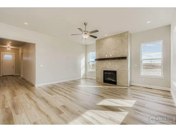 a view of a livingroom with a fireplace a ceiling fan and wooden floor