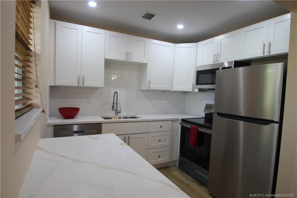 a kitchen with a refrigerator sink and cabinets