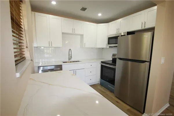 a kitchen with white cabinets and stainless steel appliances
