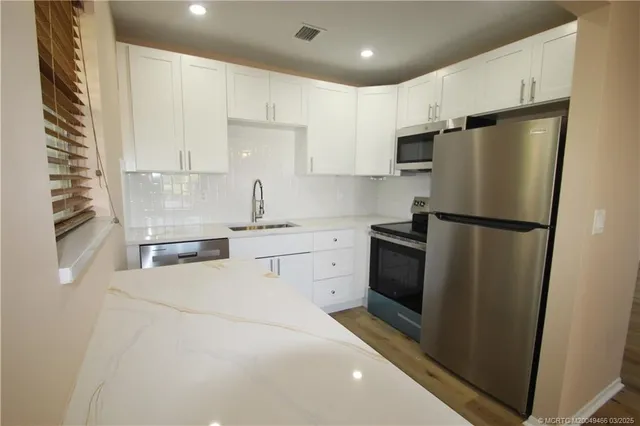 a kitchen with white cabinets and stainless steel appliances