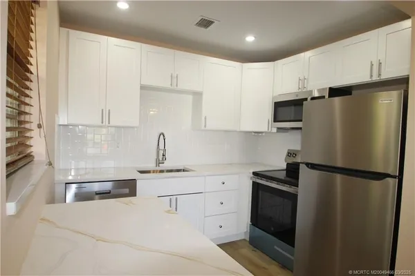 a kitchen with a refrigerator sink and cabinets