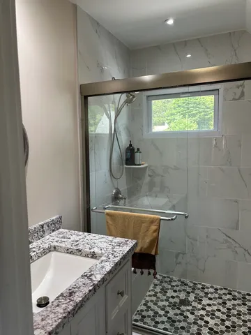 a bathroom with a granite countertop sink a toilet and shower