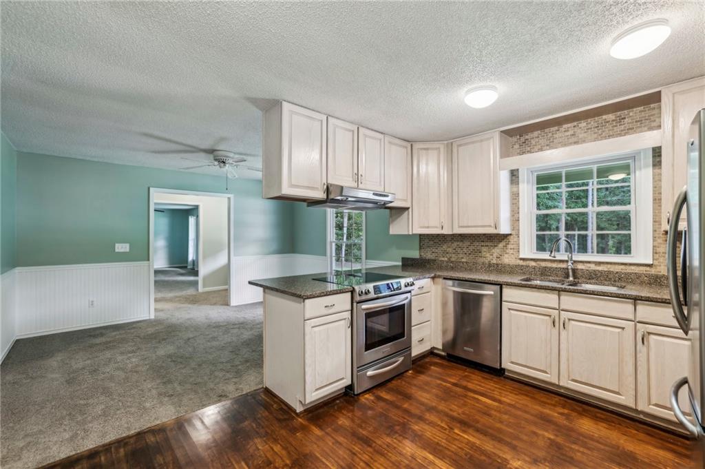 4645 Shallowford Road Roswell, GA 30075 - Photo 12 of 34 a kitchen with stainless steel appliances granite countertop a stove a sink and a microwave