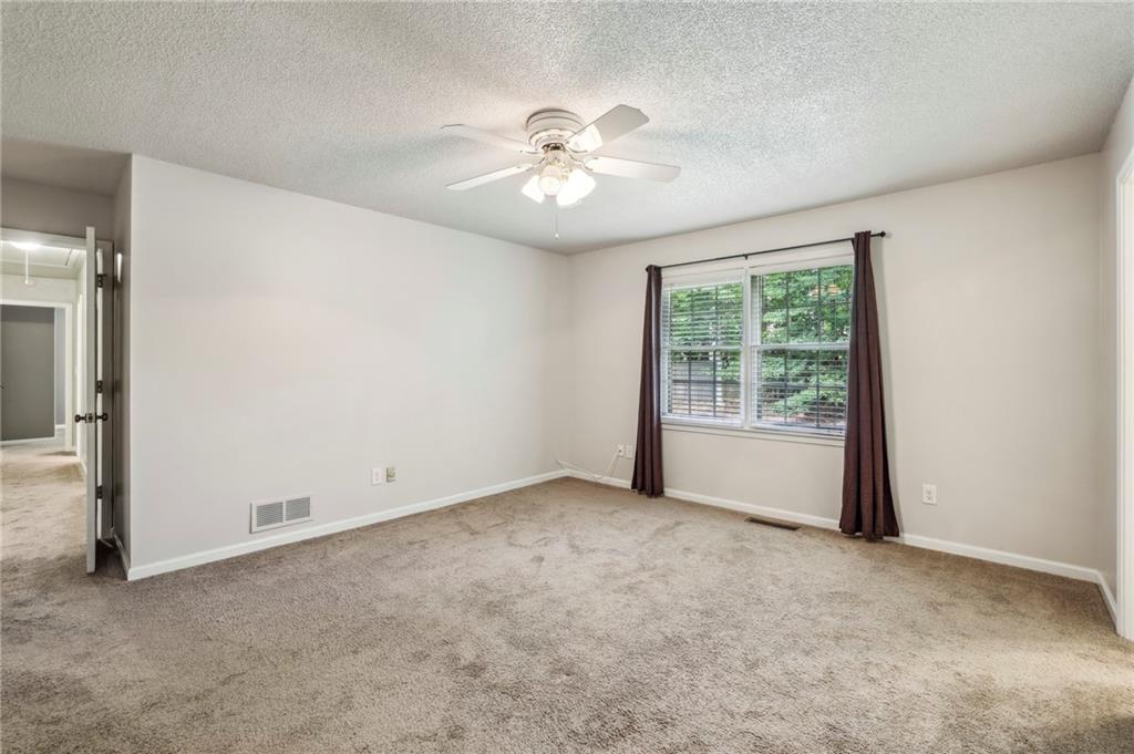 4645 Shallowford Road Roswell, GA 30075 - Photo 17 of 34 an empty room with a chandelier fan and windows