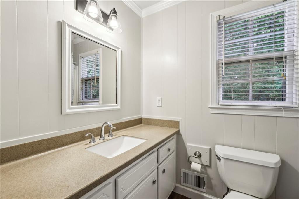 4645 Shallowford Road Roswell, GA 30075 - Photo 18 of 34 a bathroom with a granite countertop toilet a sink a mirror and a window