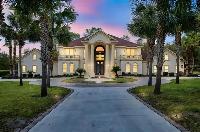 a front view of a house with garden and trees