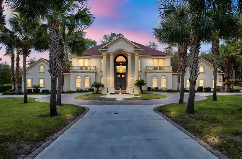 a front view of a house with garden and trees