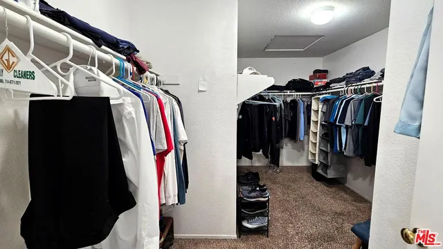 a view of walk in closet with clothes and shoes