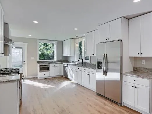 a kitchen with stainless steel appliances a refrigerator sink stove and white cabinets