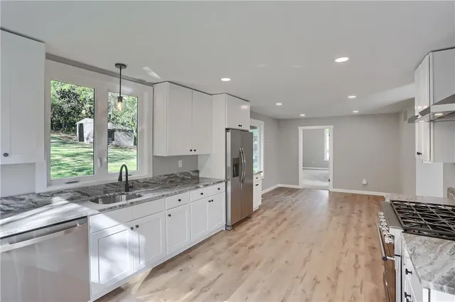 a kitchen with stainless steel appliances granite countertop a sink stove and refrigerator
