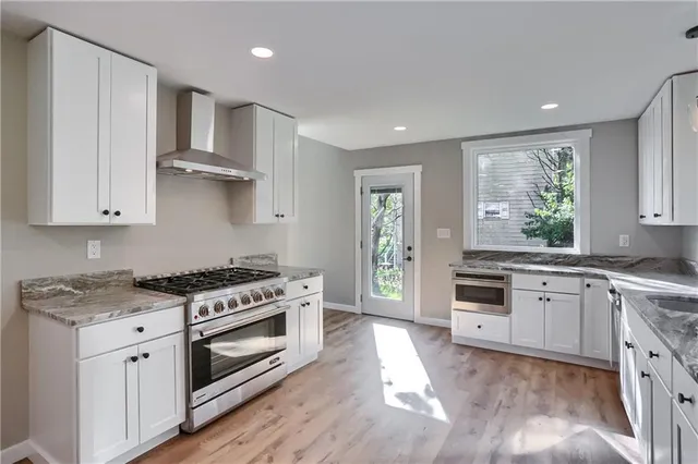 a kitchen with stainless steel appliances granite countertop a stove a sink and a white cabinets