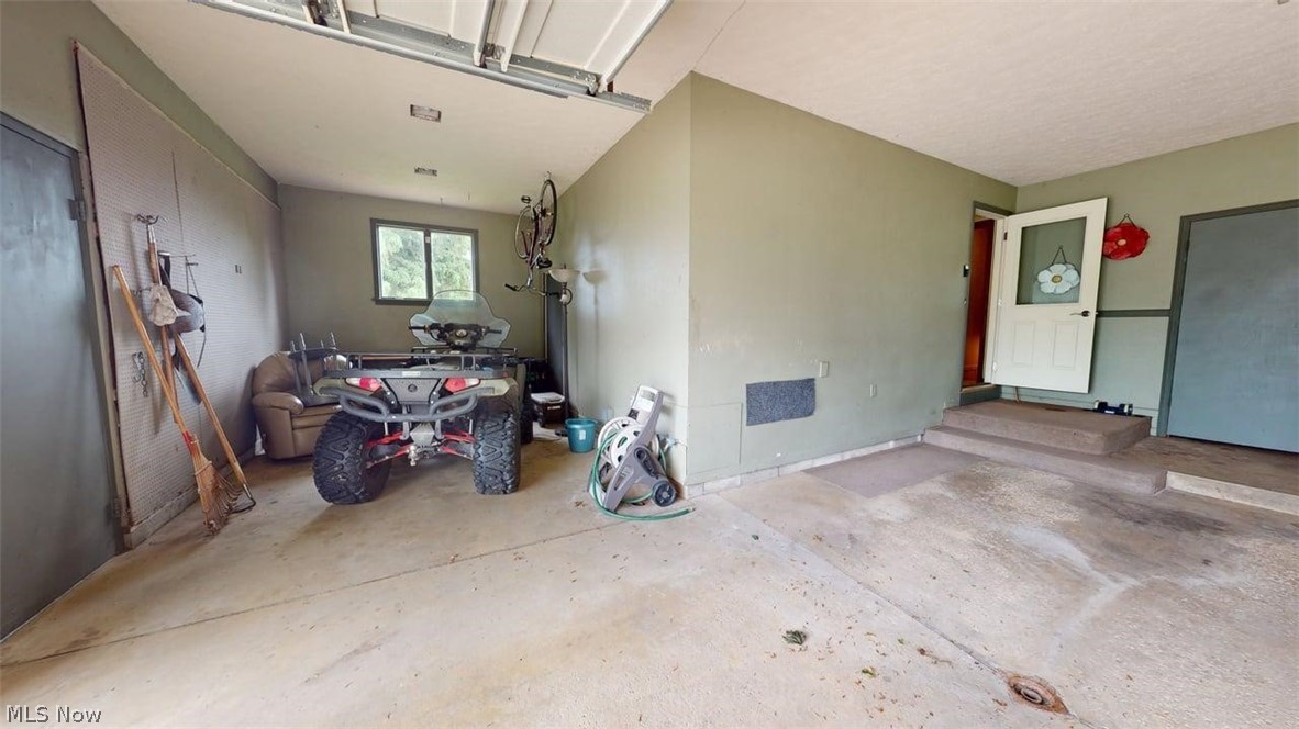 3985 Wiers Road Willard, OH 44890 - Photo 38 of 50 Spacious two-car garage featuring a concrete floor, painted walls, a window for natural light and storage area for lawn equipment