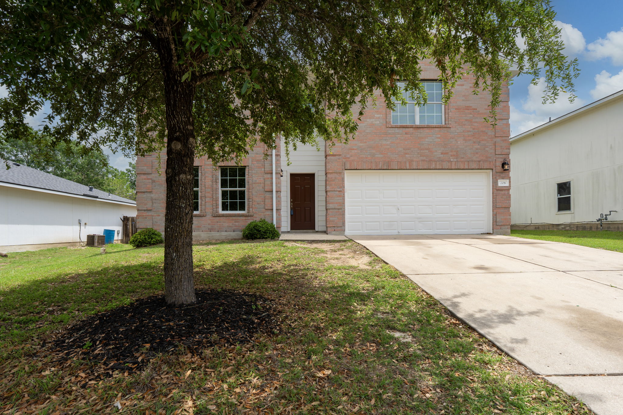 208 Dandelion Loop Kyle, TX 78640 - Photo 2 of 39 The property features a brick exterior, an attached garage with a white door, and a concrete driveway