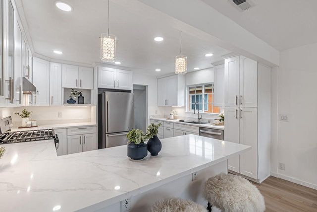 a kitchen with a refrigerator a sink dishwasher with a dining table and chairs