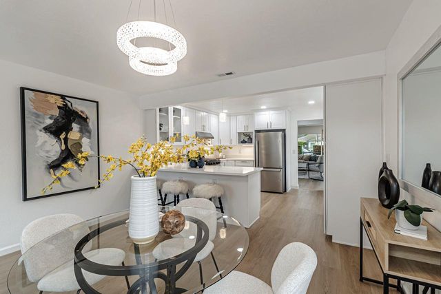 a kitchen with stainless steel appliances kitchen island granite countertop a dining table chairs and a refrigerator